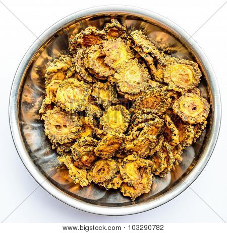 Tasty fried bittergourd chips kept on a stainless steel container on a plain background