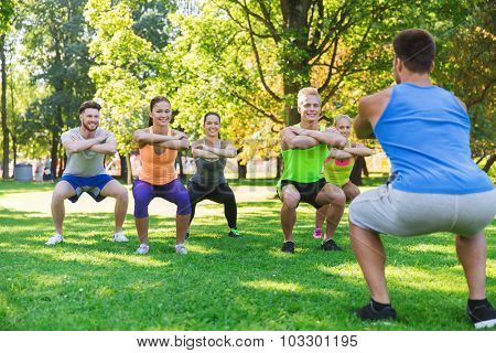 fitness, sport, friendship and healthy lifestyle concept - group of happy teenage friends or sportsmen exercising and doing squats at boot camp