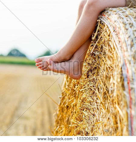 Little Kid Boy Sitting On Hay Bale In Summer