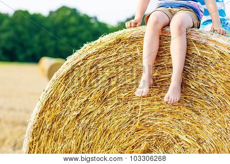 Little Kid Boy Sitting On Hay Bale In Summer