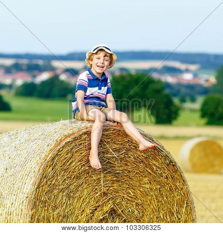 Little Kid Boy Sitting On Hay Bale In Summer