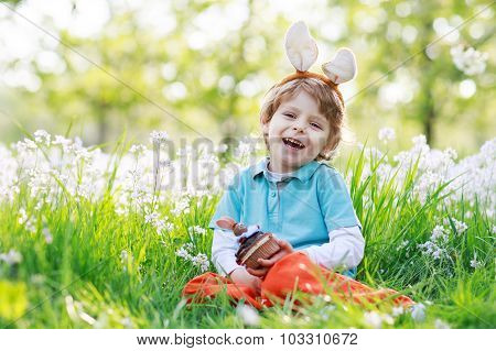Cute Happy Little Boy Wearing Easter Bunny Ears And Eating Choco
