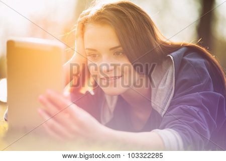 Beautiful Girl With Tablet Or Ebook Outdoor Laying On Field