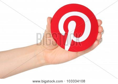 Hand holds Pinterest logotype printed on paper
