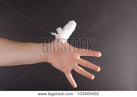 Injured bandaged finger on dark background