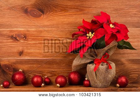Christmas decoration - artificial red poincettia flower wrapped in sackcloth with red balls on the w