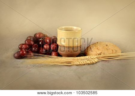 Communion table with cup of wine, grapes, bread and wheat