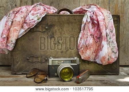 Traveling Concept Of Retro Consists Suitcase, Camera, Sunglasses, Mouth Organ And Shawl On Wood Back