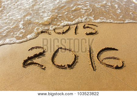 2015 and 2016 year written on sandy beach sea. Wave washes away 2015.