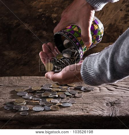 caucasian old man's hands and pile of old coins