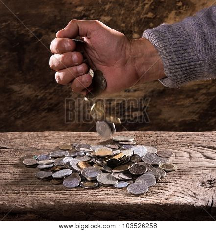 caucasian old man's hands and pile of old coins