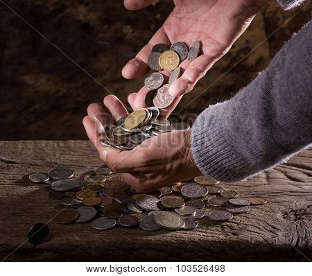 caucasian old man's hands and pile of old coins