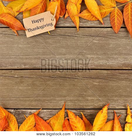 Happy Thanksgiving tag with frame of autumn leaves on wood