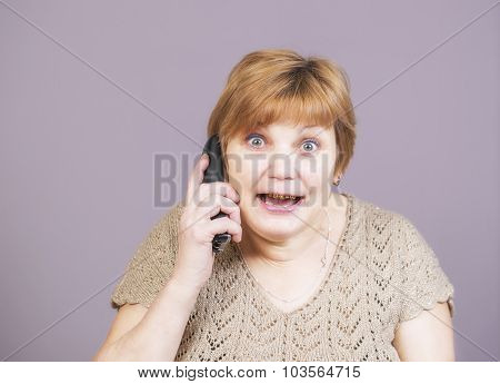 Very emotional golden teeth woman with the telephone handset on a gray background