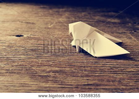 an origami bird on a rustic wooden surface, with a retro effect