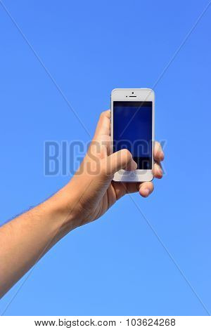 Man's Hand Holding A Phone Against The Sky