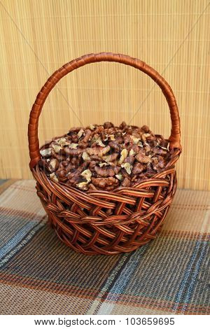 Rattan Basket With Walnut Kernels Is On A Checkered Napkin In Brown Tones
