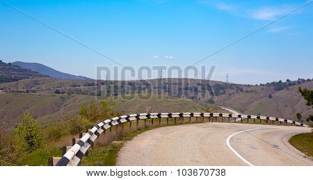 Ashalt road with safety fence among hills