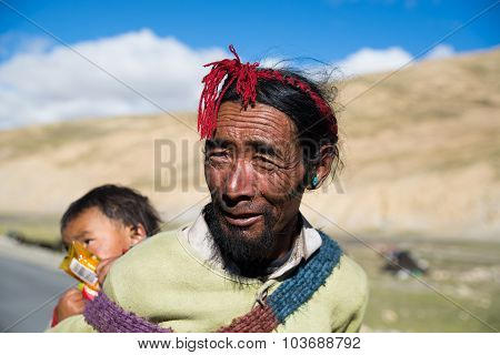 Tibetan farmer with his child in a steppe in Tibet.