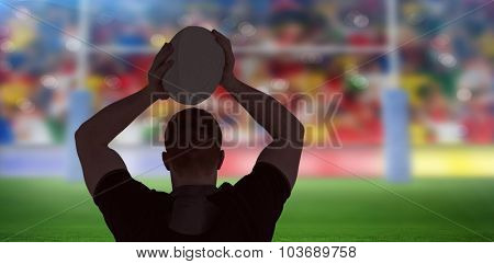 Rugby player about to throw a rugby ball against rugby stadium