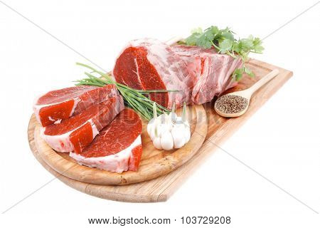 fresh meat : raw uncooked fat lamb pork rib and fillet with green stuff and red chili pepper on wooden plate isolated over white background