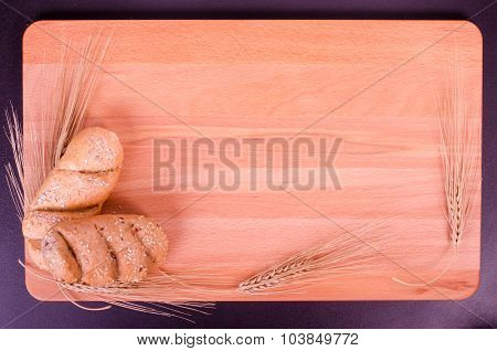 Fresh buns, cookies and wheat ears in a wood background