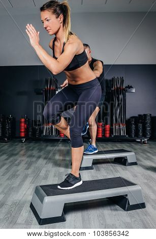 Couple doing exercises over steps in fitness center