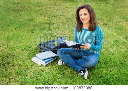 Young ethnic woman doing school work outside