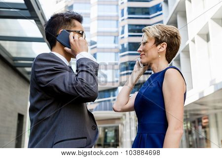 Business people standing in stret with their mobiles