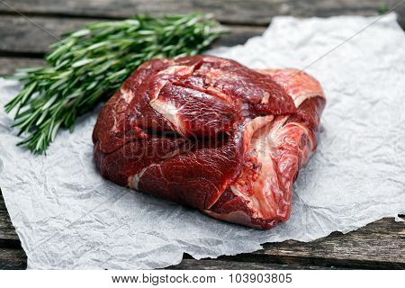 Raw Ox Cheek On Crumpled Paper,  Decorated With Vegetables. On Old  Wooden Table