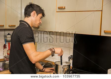 Young Man Cooking Food on Stove