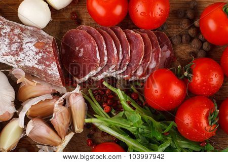 Salami With Cherry Tomatoes, Ruccola And Garlic On A Cutting Board