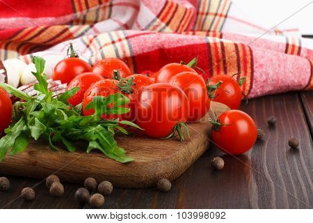 Cherry Tomatoes, Rucola, Spices, Garlic And Salami On A Cutting Board