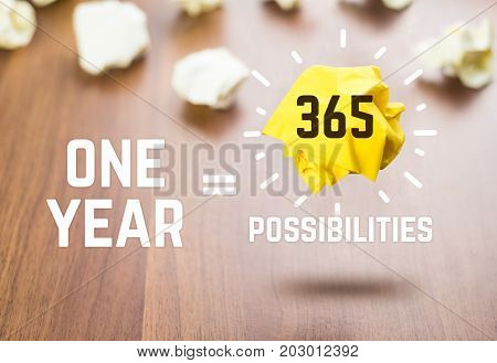 Inspiration quoteOne year equal 365 possibilities whit yellow paper ball floating at dark brown table topMotivational typographic.