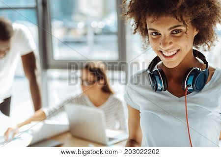 Onlu positivity. Portrait of a positive curly young afro american woamn smiling while her university friends sitting at the table and studying