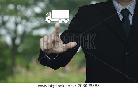 Businessman pressing truck flat icon over blur flower and tree in park Business transportation service concept