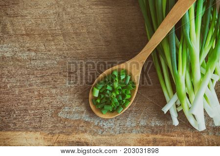 Fresh spring onion on rustic wood table.Close up on chopped scallions or spring onion in top view flat lay. 