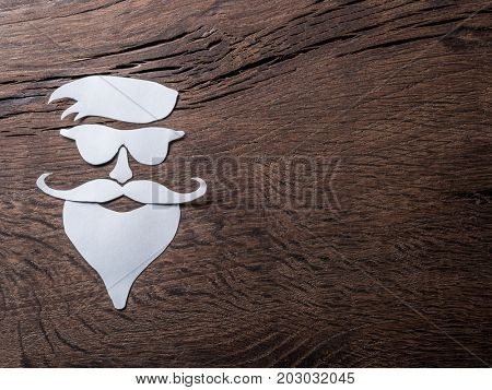 Hipster's definicial facial look cut from paper on the wooden background.