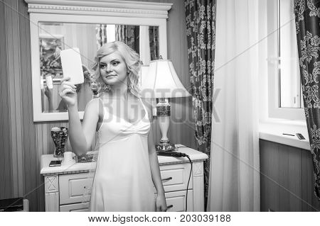 Morning of the bride. The blonde bride looks in the mirror.