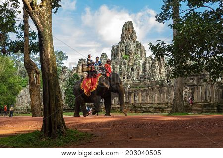 SIEM REAP CAMBODIA - SEPTEMBER 1 2015: Tourists ride elephants along the road around the Bayon temple at the Angkor Wat complex.