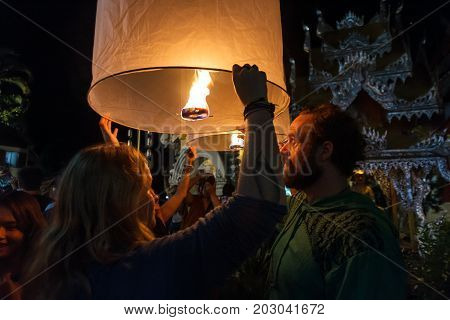 CHIANG MAI THAILAND - 12/30/2015: Tourists release floating lanterns at a Buddhist temple on New Year's Eve in Chiang Mai Thailand.