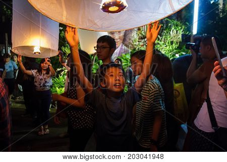 CHIANG MAI THAILAND - 12/30/2015: A young boy releases a floating lantern at a temple on New Year's Eve in Chiang Mai Thailand.