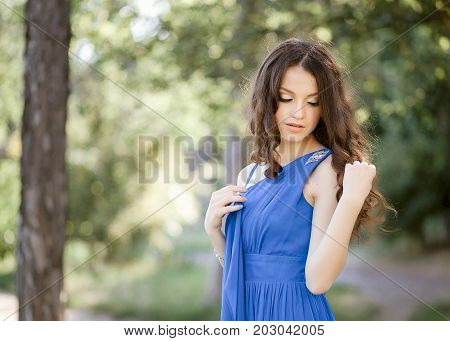 A charming shy brown-haired woman in blue attire hides her eyes.