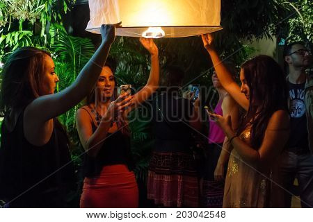 CHIANG MAI THAILAND - 12/30/2015: Young female tourists release a floating lantern at a Buddhist temple on New Year's Eve in Chiang Mai Thailand.