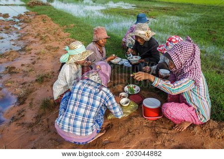 SIEM REAP CAMBODIA - SEPTEMBER 12 2015: Rice farmers take a moment to eat before working in the fields.