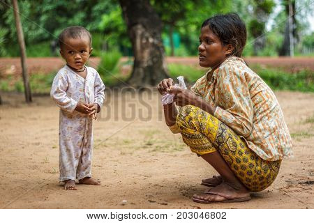 SIEM REAP CAMBODIA - 9/12/2015: A mother crouches next to her boy in a village.