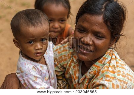 SIEM REAP CAMBODIA - 9/12/2015: A mother crouches next to her children in a village.