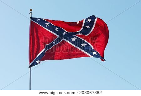 Confederate rebel flag waving in the wind against the blue sky background in Charleston South Carolina USA.