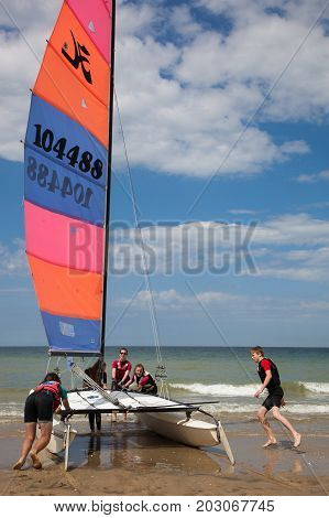 Cabourg France - August 1 2017: On the beach in the town of Cabourg Normandy France. Young teenagers take sailing lessons on small Catamarans