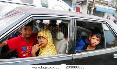 NARATHIWAT, THAILAND--Photo of seven excited children plus the driver all squeezed into one car in Narathiwat, Thailand in March 2016.